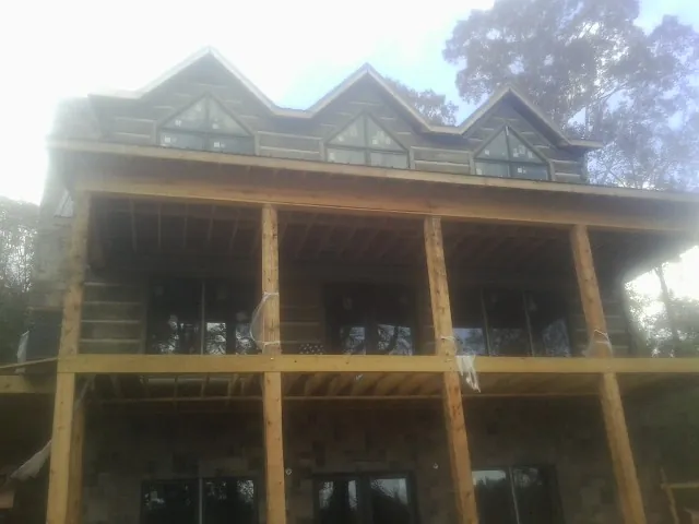 Dormers and porch framing on a large log home under construction — Roof Coating work by our crew in Broad Brook