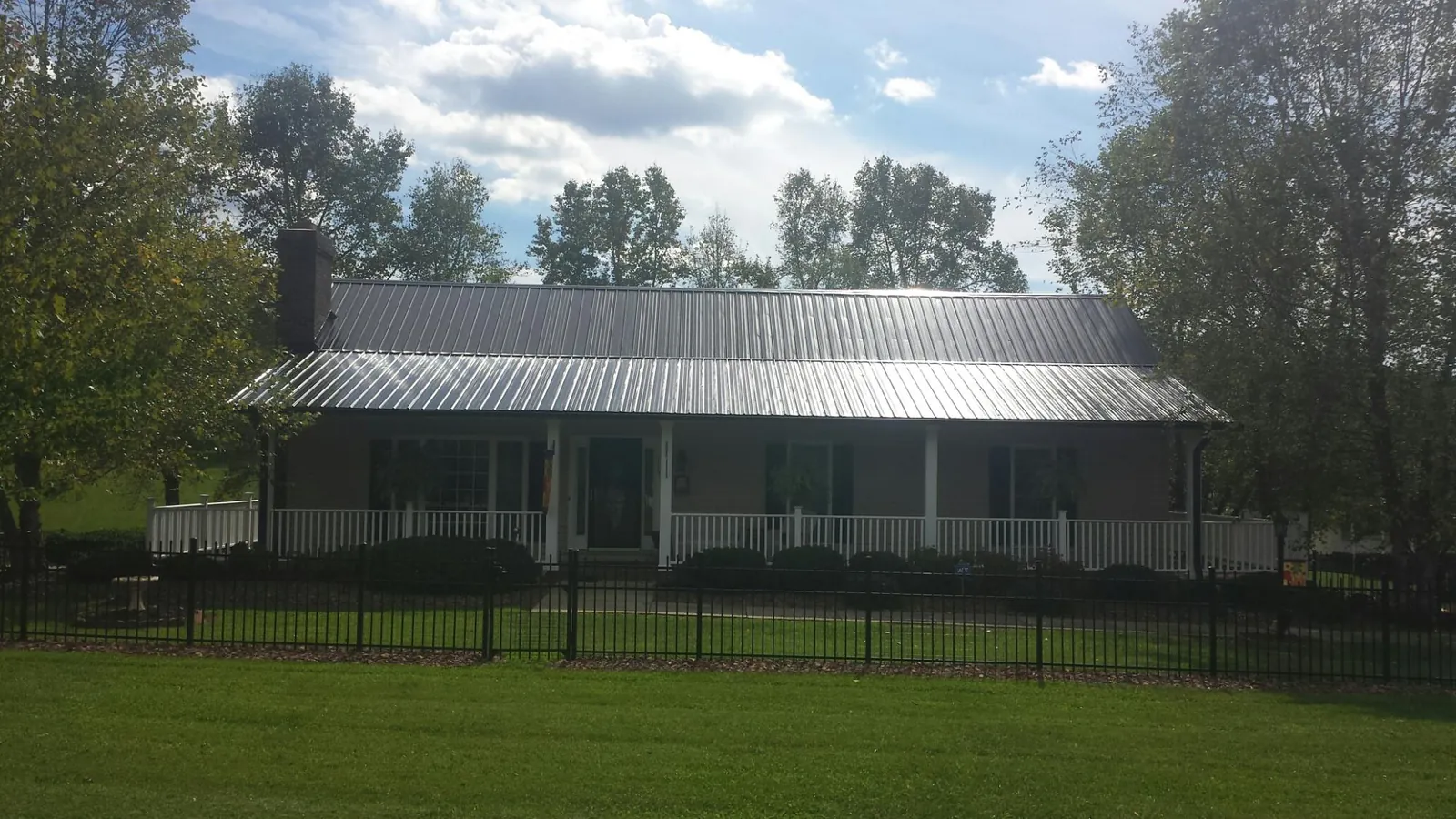 Gray metal roof on a brick ranch with a full width front porch — Gutter Guard Installation work by our crew in Broad Brook